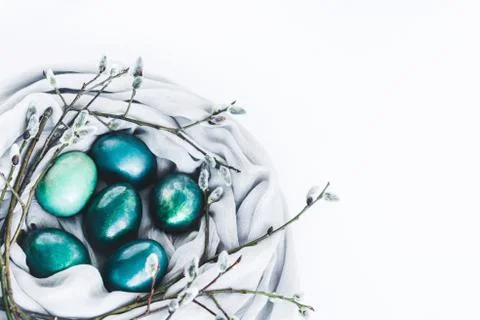 Nest of fabric with turquoise colored Easter eggs decorated with pussy willow on Stock Photos