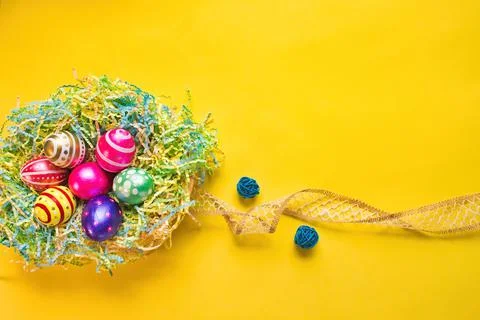 A Nest of Hand Painted Easter Eggs on Yellow Background Stock Photos
