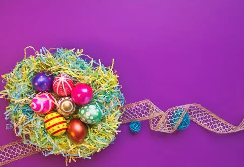 A Nest of Hand Painted Easter Eggs on Purple Background Stock Photos