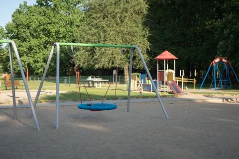 Nest swing stands on the sand at empty children playground in public park Stock Photos