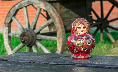 Nested doll on the background of an old wooden cart. Matryoshka. Stock Photos