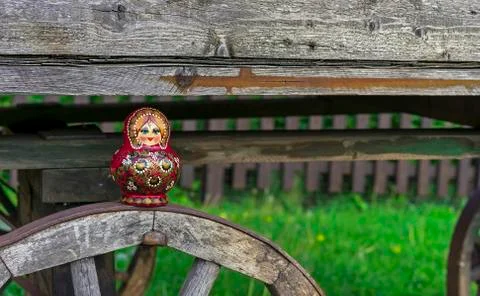Nested doll on the background of an old wooden cart. Matryoshka. Stock Photos