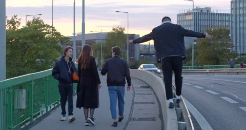 Nested youth moving across bridge He steps along the parapet balances foot 스톡 동영상 229633687