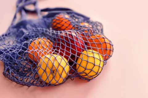 Net bag with fruit on bright background. Zero waste and ecology conservation Stock Photos