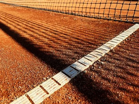 Net shadows on the classic orange clay tennis court with white lines Stock Photos