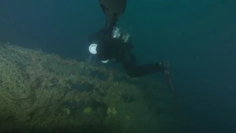Net wraps the wreck Adernò from hull to bow with diver passes and rainbow wrasse Stock Footage 228065079