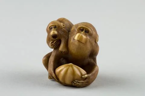 Netsuke of a Female Monkey Holding a Nut while her Baby Crawls on her Back .. Stock Photos