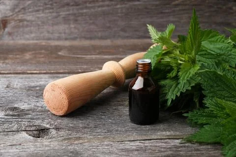 Nettle leaf extract in bottle and pestle on wooden background Foto stock