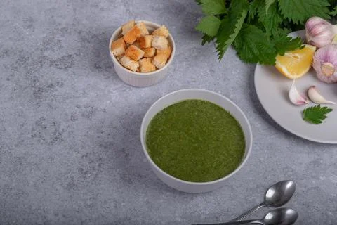 Nettle soup and wild garlic, onion, lemon and crackers. Healthy vegan food Stock Photos