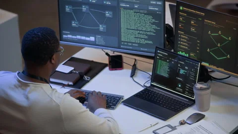 Network Administrator Reviewing Data and Codes on Computers in Office Stock Footage 334932873