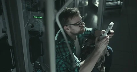 Network administrator sits on floor and puts on earphones to drown sound of Stock Footage 107919596