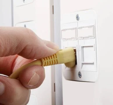 Network cable Cable guy inserting a network cable into the slot on the wal... 스톡 사진