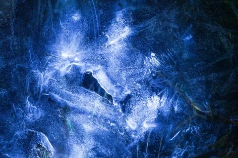 Network of cracks in thick solid frozen layer of ice with shining light Foto stock