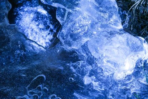 Network of cracks in thick solid frozen layer of ice with shining light 写真素材