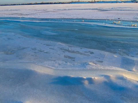 Network of cracks in thick solid layer of ice of a frozen river Stock Photos