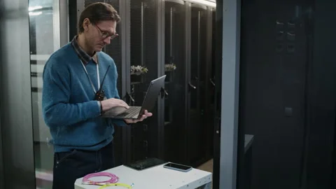 Network Engineer Coding on Laptop while Coordinating Data Center Operations Stock Footage 330542087