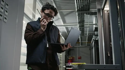 Network Engineer Communicating on Radio and Checking Laptop in Data Center Stock Footage 330539370