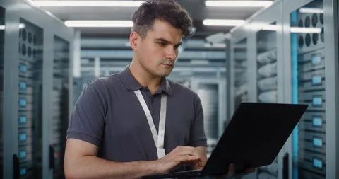 Network Engineer Configuring Server Racks with Laptop in Data Center Stock Footage 344880489