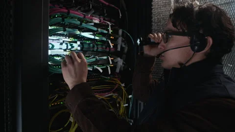 Network Engineer Inspecting Server Rack with Flashlight in Data Center Stock Footage 330546066