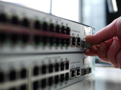 Network engineer inspects fiber cable on computer switch Stock Photos