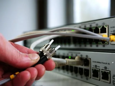Network engineer inspects fiber cable on computer switch Stock Photos