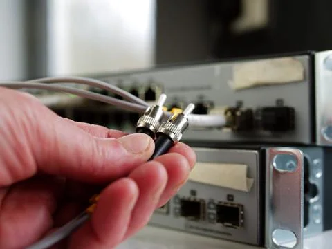 Network engineer inspects fiber cable on computer switch Stock Photos