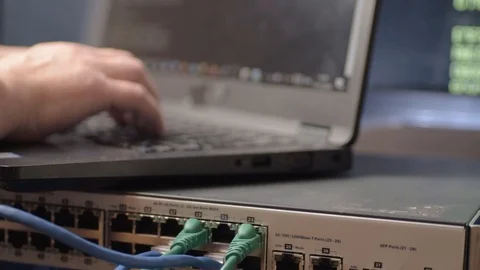 Network engineer typing and connecting Ethernet cables to switch Stock Footage 120396741
