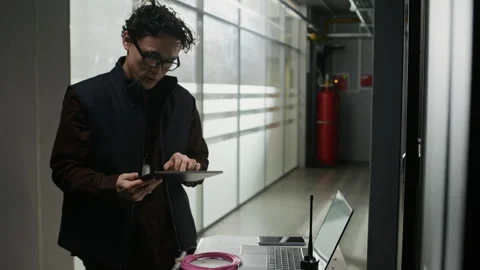 Network Engineer Using Laptop and Tablet while Configuring Server Equipment Stock Footage 330540883