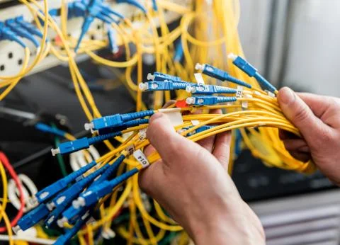 Network engineer working in server room. Connecting network cables to switches 写真素材