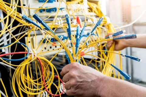 Network engineer working in server room. Connecting network cables to switches Stock Photos