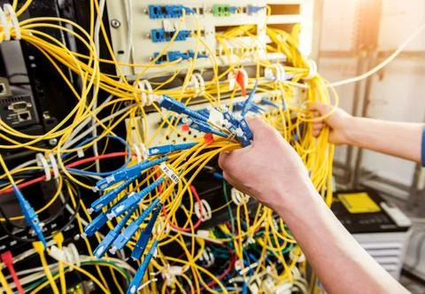 Network engineer working in server room. Connecting network cables to switches Stock Photos