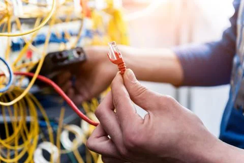 Network engineer working in server room. Connecting network cables to switches 写真素材