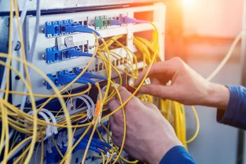 Network engineer working in server room. Connecting network cables to switches Stock Photos
