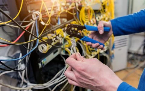 Network engineer working in server room. Connecting network cables to switches Stock Photos