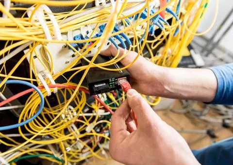Network engineer working in server room. Connecting network cables to switches Stock Photos