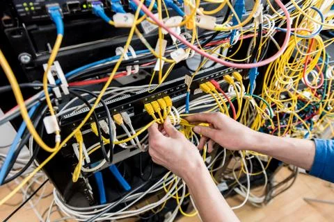 Network engineer working in server room. Connecting network cables to switches Stock Photos
