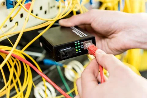 Network engineer working in server room. Connecting network cables to switches Stock Photos