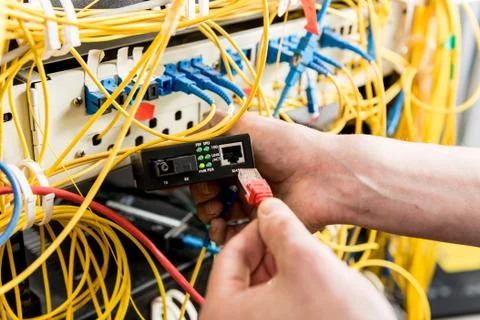 Network engineer working in server room. Connecting network cables to switches Stock Photos