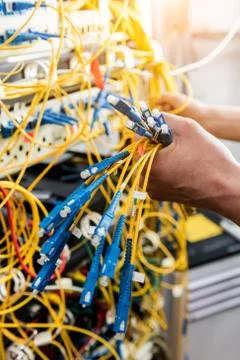 Network engineer working in server room. Connecting network cables to switches Stock Photos