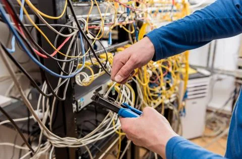 Network engineer working in server room. Connecting network cables to switches Stock Photos