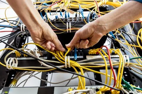 Network engineer working in server room. Connecting network cables to switches 写真素材