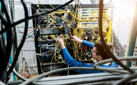 Network engineer working in server room. Connecting network cables to switches Stock Photos