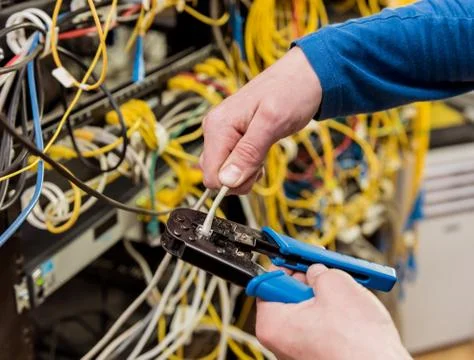Network engineer working in server room. Connecting network cables to switches Stock Photos