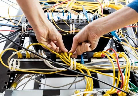 Network engineer working in server room. Connecting network cables to switches 写真素材