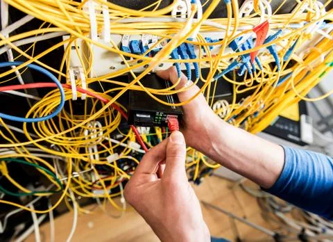 Network engineer working in server room. Connecting network cables to switches 写真素材