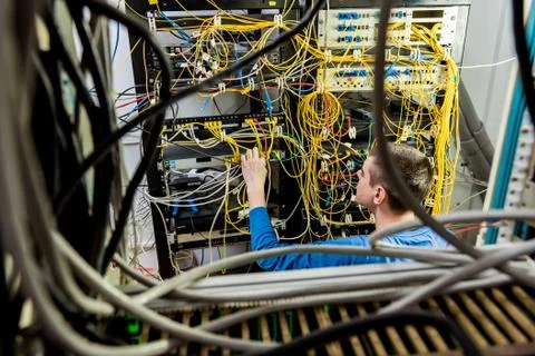 Network engineer working in server room. Connecting network cables to switches Stock Photos