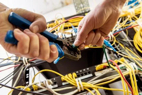 Network engineer working in server room. Connecting network cables to switches Stock Photos