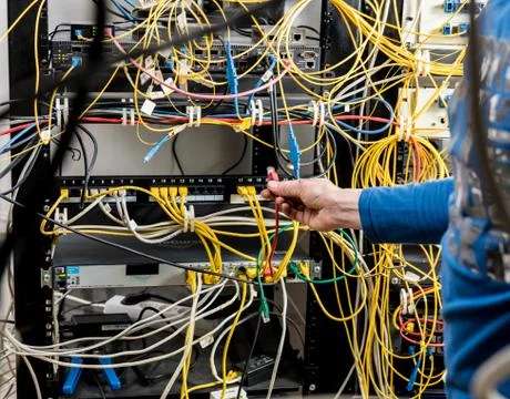 Network engineer working in server room. Connecting network cables to switches Stock Photos