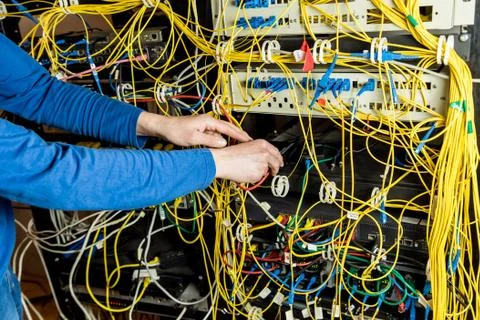 Network engineer working in server room. Connecting network cables to switches Stock Photos