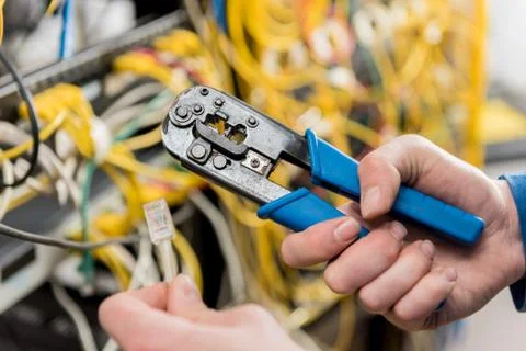 Network engineer working in server room. Connecting network cables to switches Stock Photos